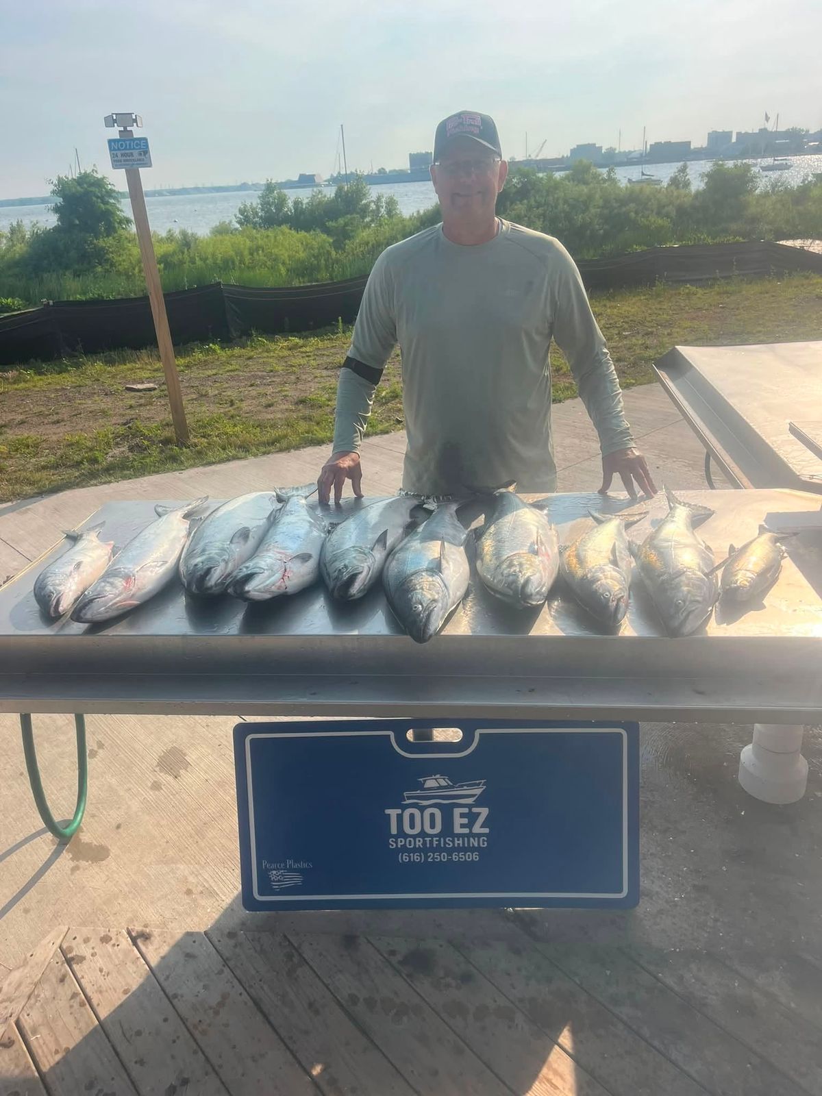 Captain Anthony Sova displays a catch of multiple fish at the dock in Muskegon with the waterfront behind