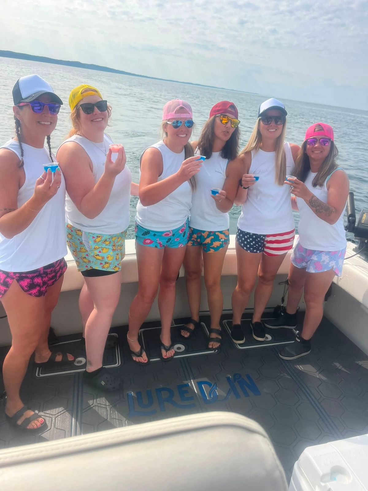 A group of six people in swim attire stand together on the deck of the charter boat on Lake Michigan