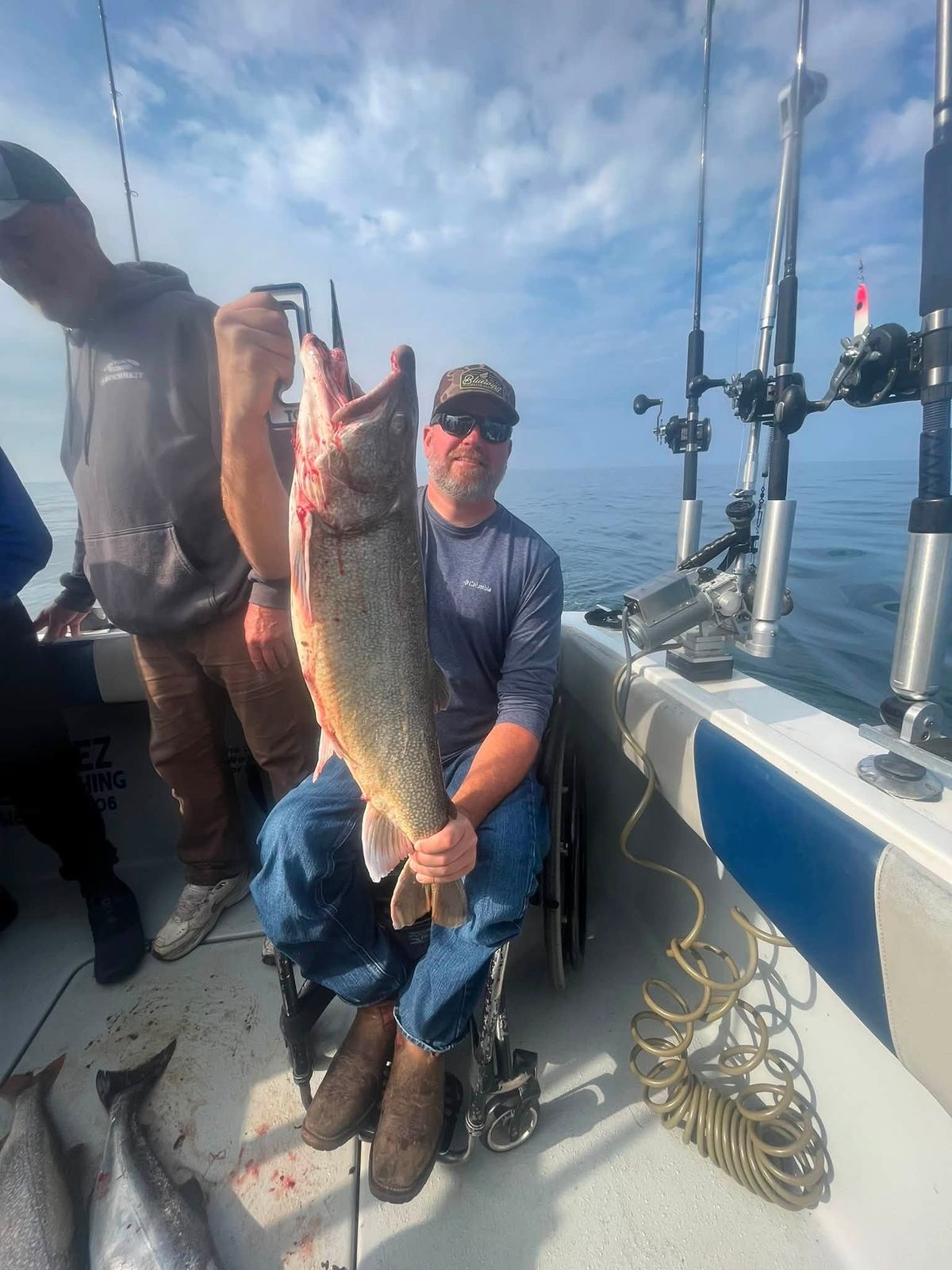 A guest holds up a large lake trout aboard the Cherokee charter boat