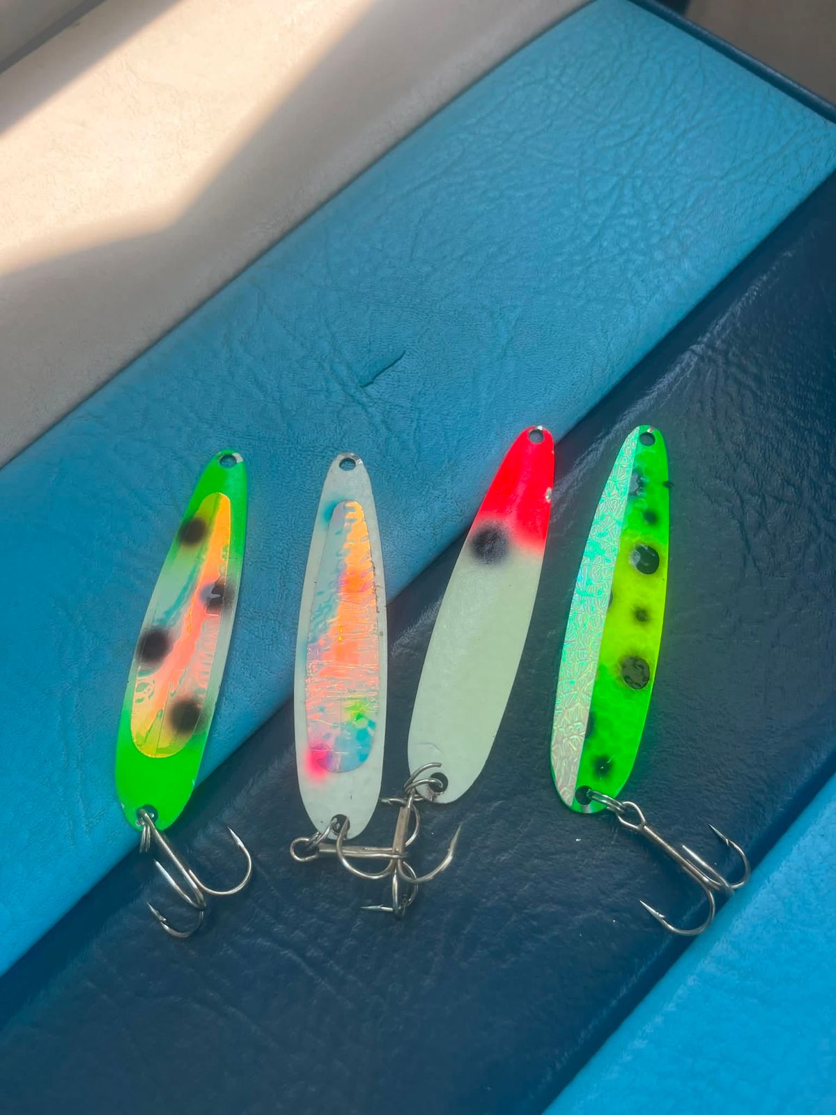 Four colorful fishing lures laid out on the boat's blue gunwale