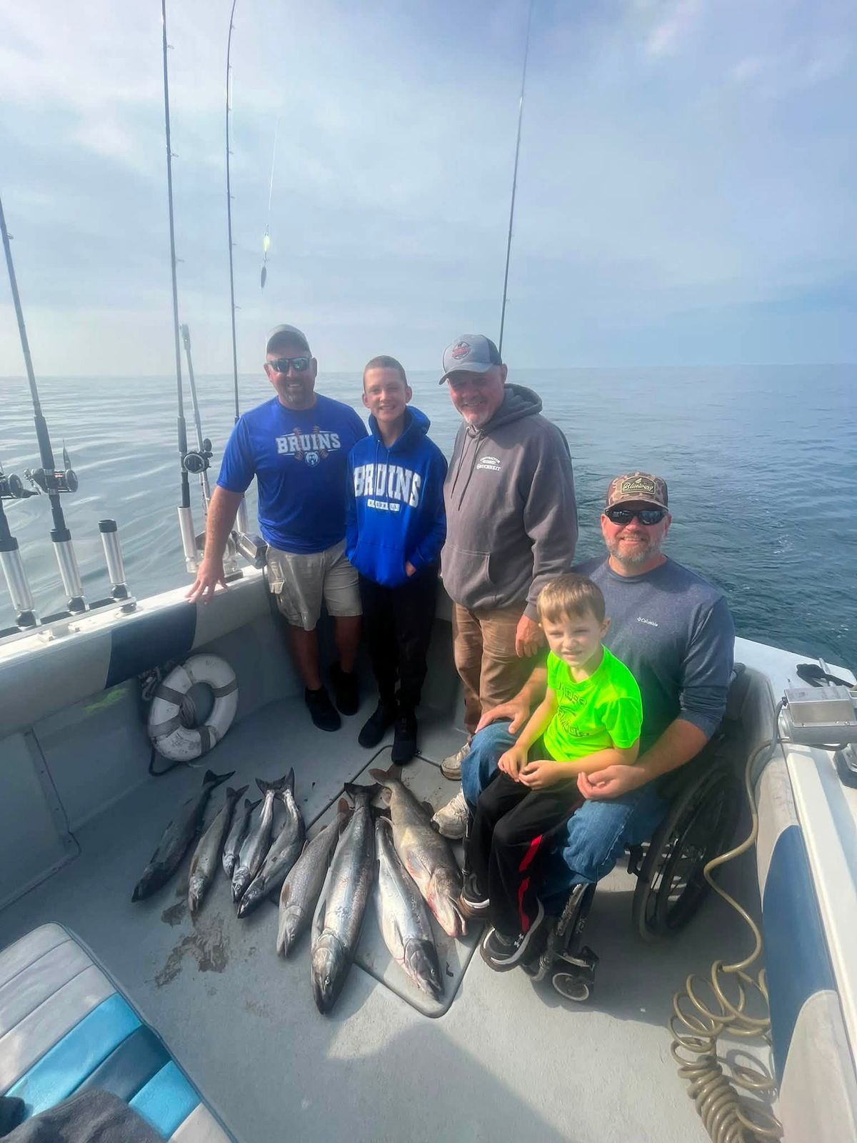 Five passengers with their catch of multiple fish on the boat deck
