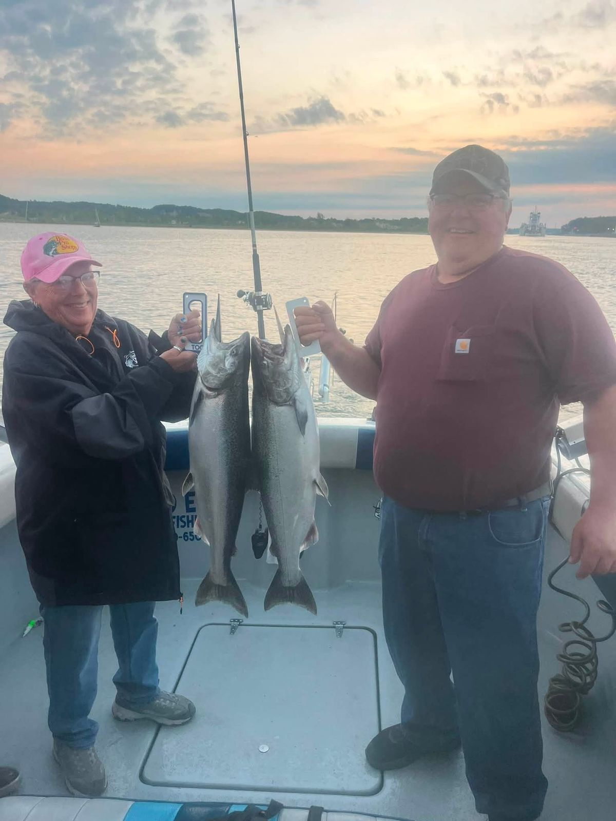 Two anglers display two large Lake Michigan salmon aboard the charter boat at sunset