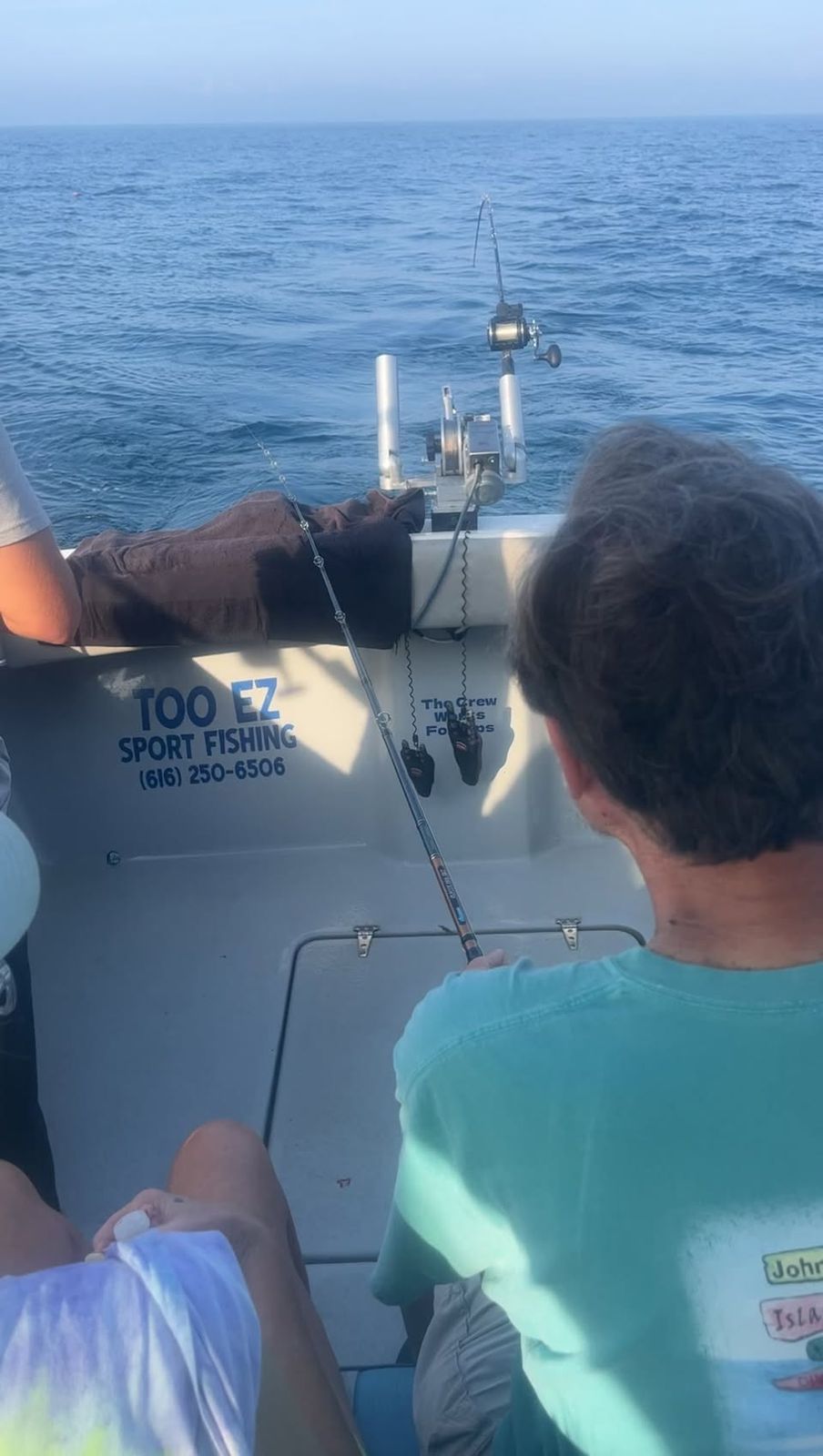 Passengers aboard the Too Ez charter boat on Lake Michigan with rigging overhead