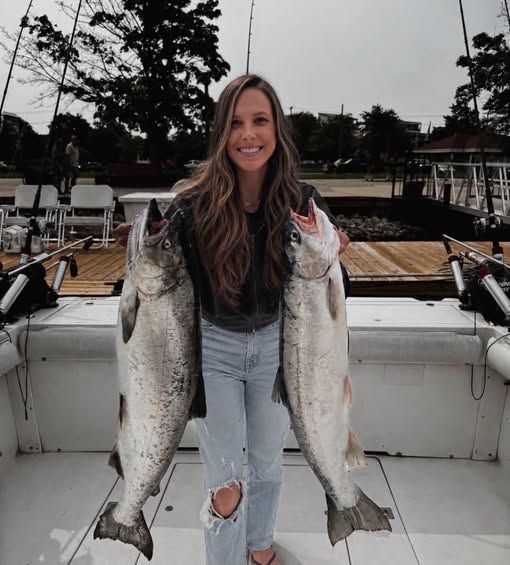 A woman displays two large lake trout caught on the Too Ez charter boat