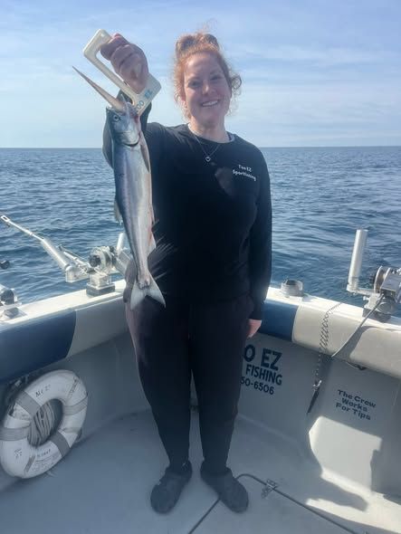 An angler holds a freshly caught fish aboard the Too Ez charter boat