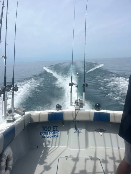 The stern of the Too Ez Cherokee charter boat cutting through Lake Michigan with rods mounted and wake behind