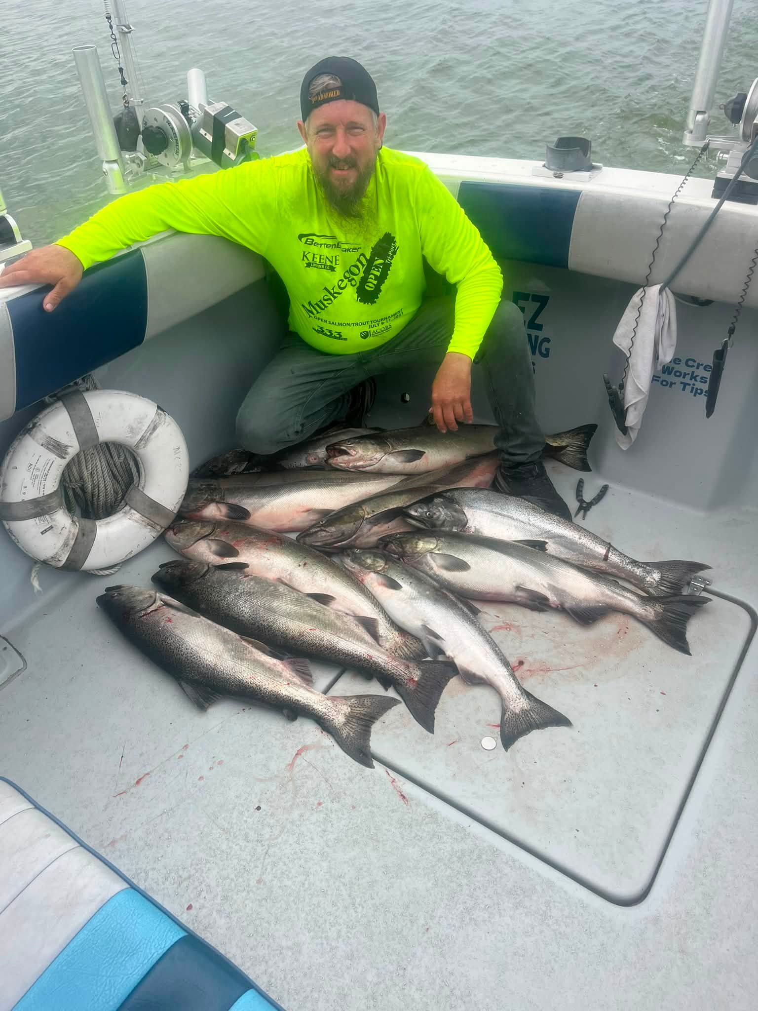 A fishing guide displays a successful catch of large silver fish on the boat deck.