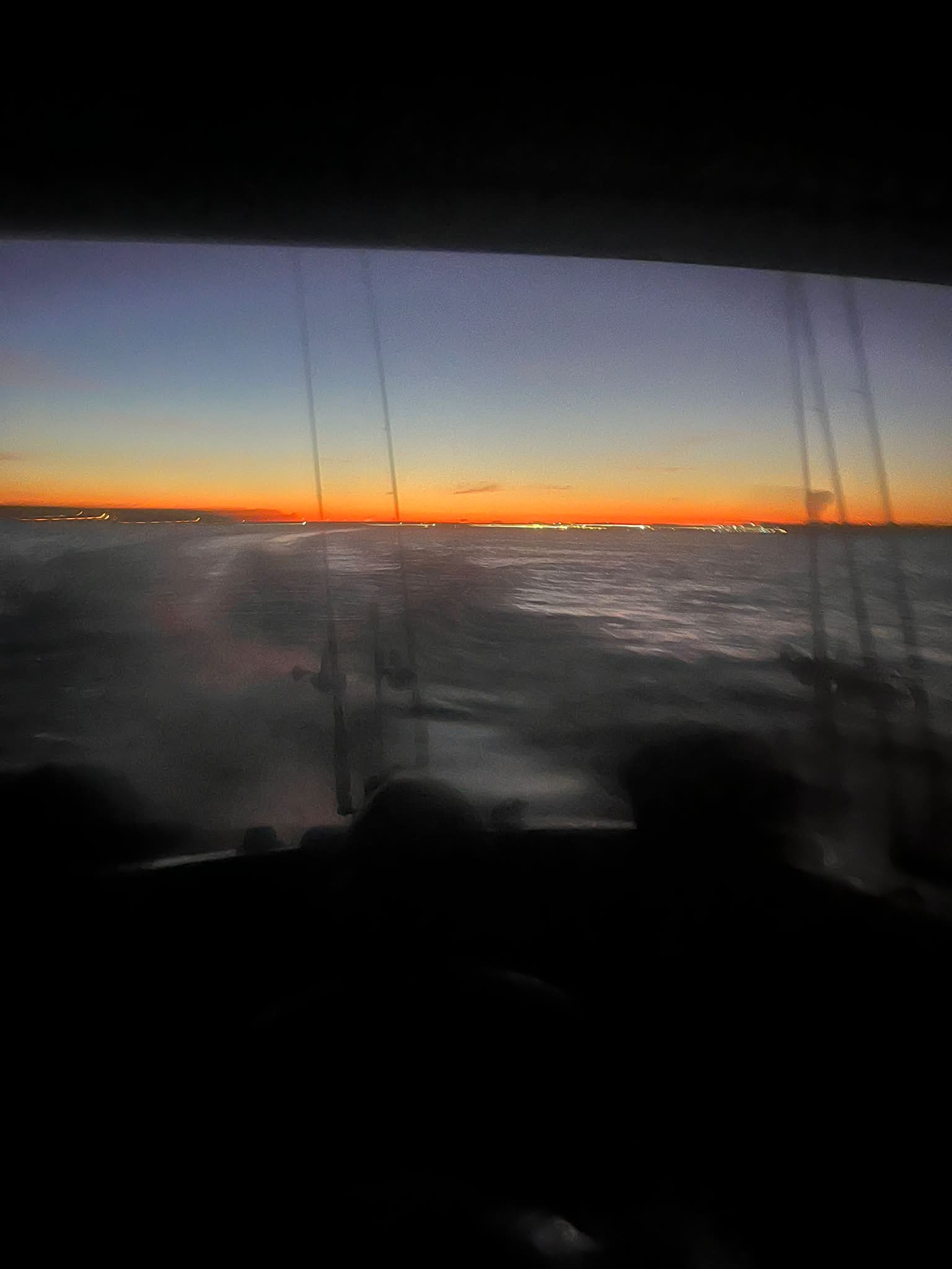 Sunset view from a fishing boat showing the calm water and orange horizon during an evening charter excursion.