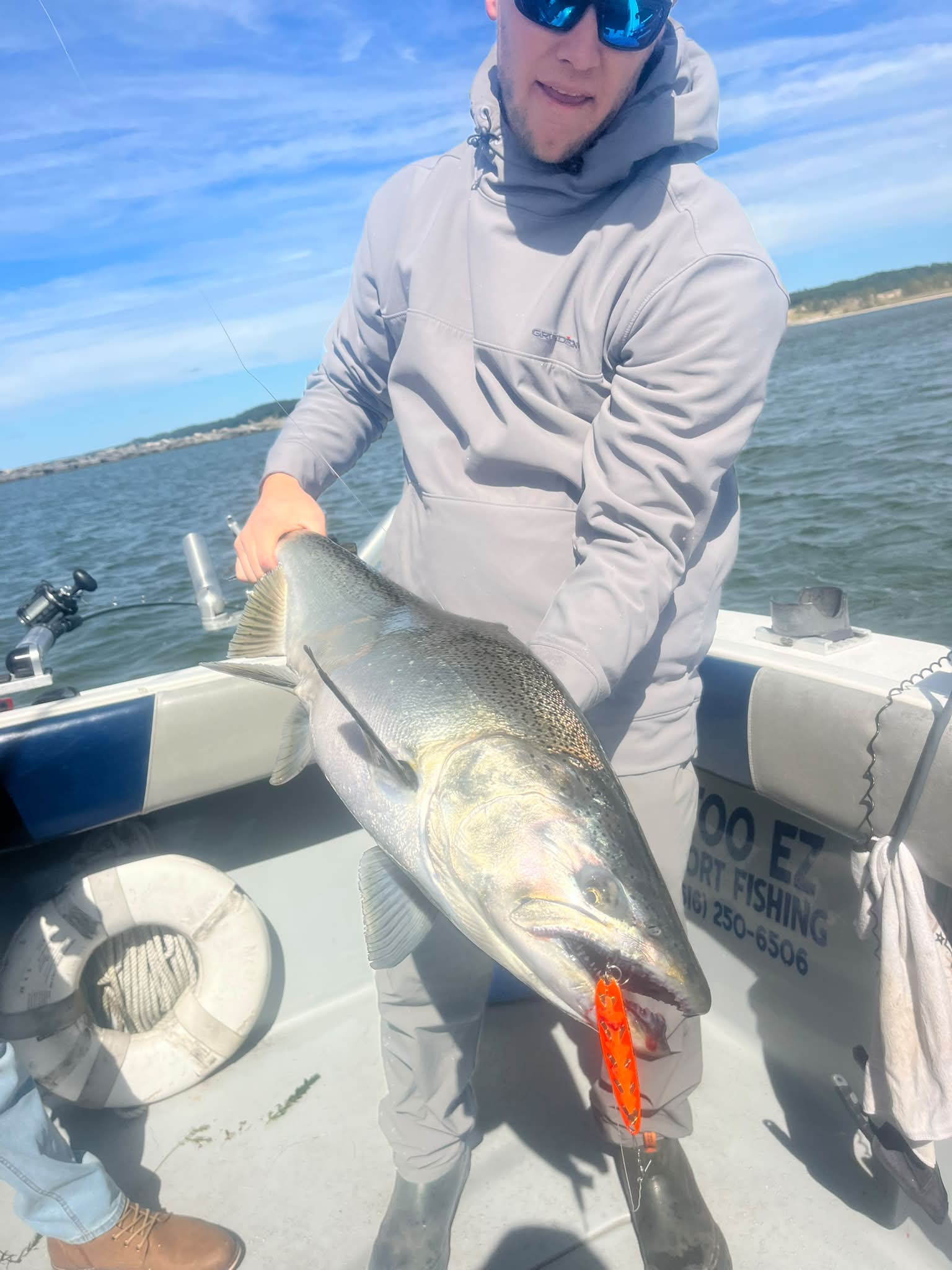 A successful catch displayed on a Too Ez Sportfishing charter boat, with an angler holding a large walleye or pike against Lake Michigan waters.