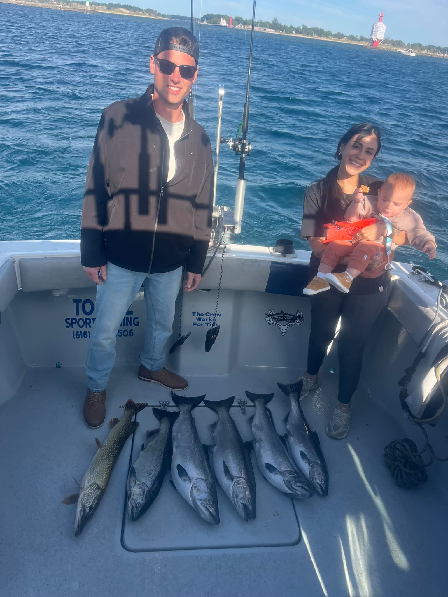 A successful fishing charter with customers displaying their catch of multiple fish aboard the Too Ez Sportfishing boat on the water.